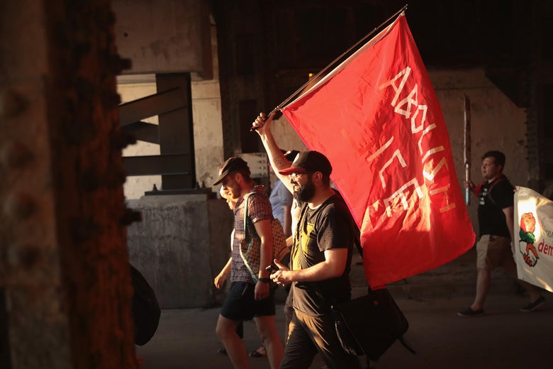 A demonstrator holds a red flag that says, "Abolish ICE"